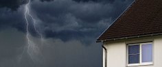 Ein Unwetter braut sich über einem Haus zusammen, es blitzt und regnet