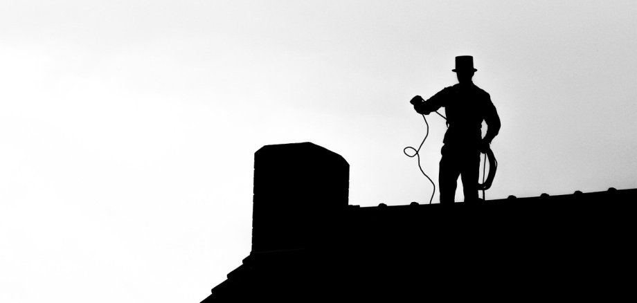 Schornsteinfeger balanciert auf einem Dachfirst